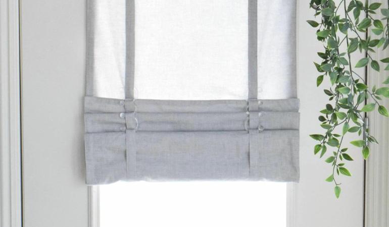 With a tiered tumble shade in Raleigh, you can block sun glare all year round. Gray rolled tumble shade on a glass door